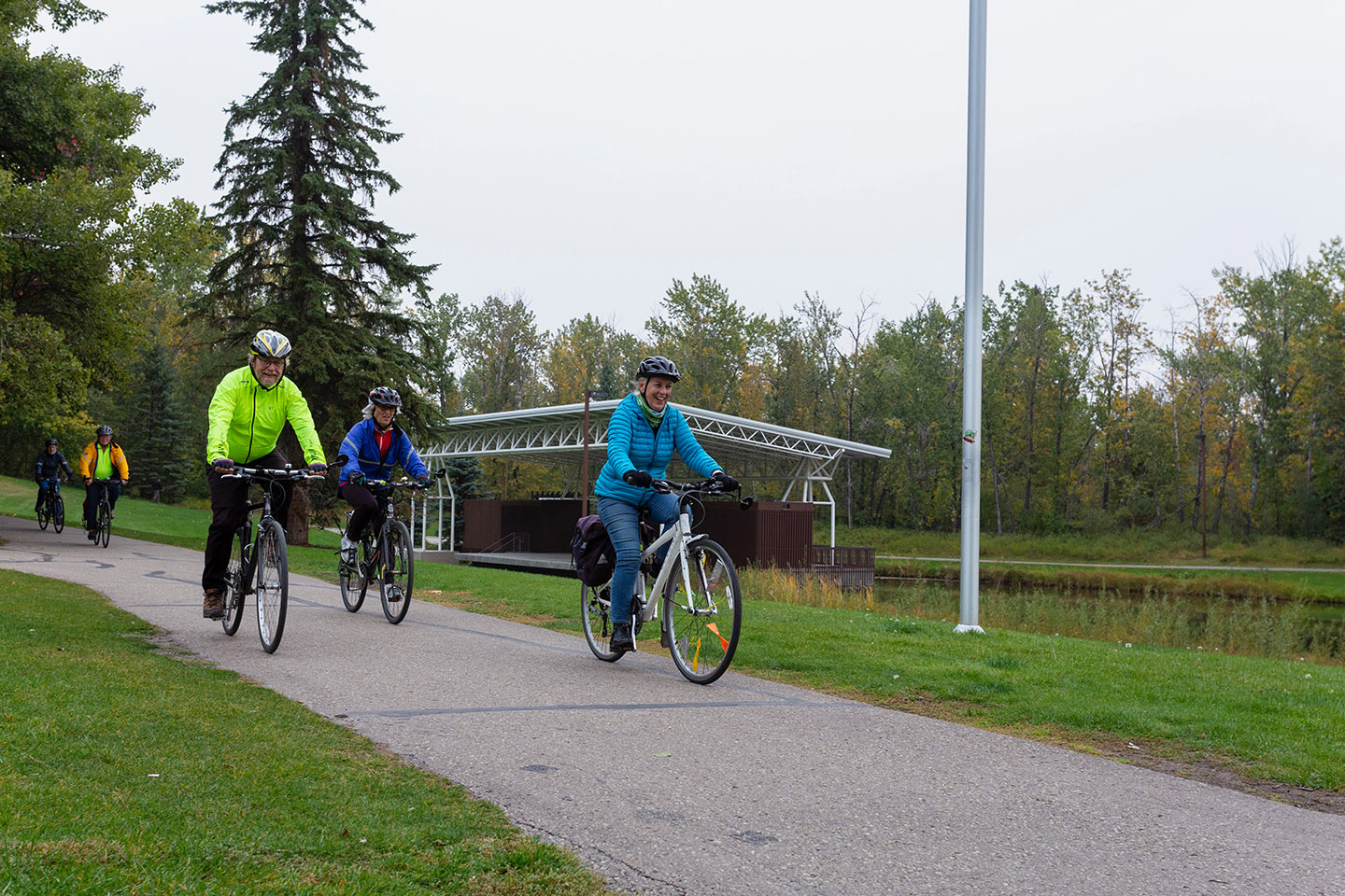 Three people riding bikes next to the water along a paved trail. 