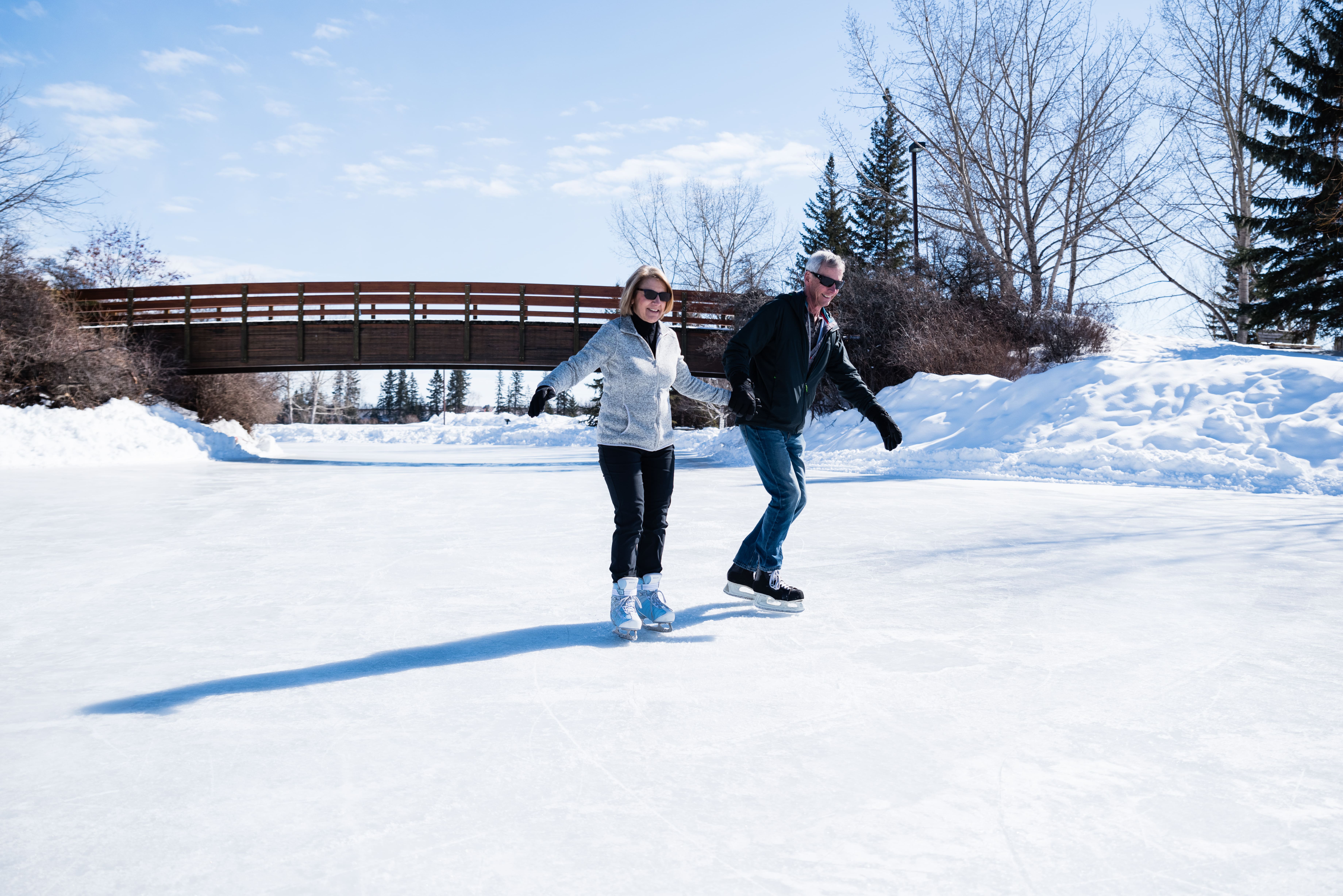 Couple ice skating on a sunny winter day at Bower Ponds in Red Deer, Alberta