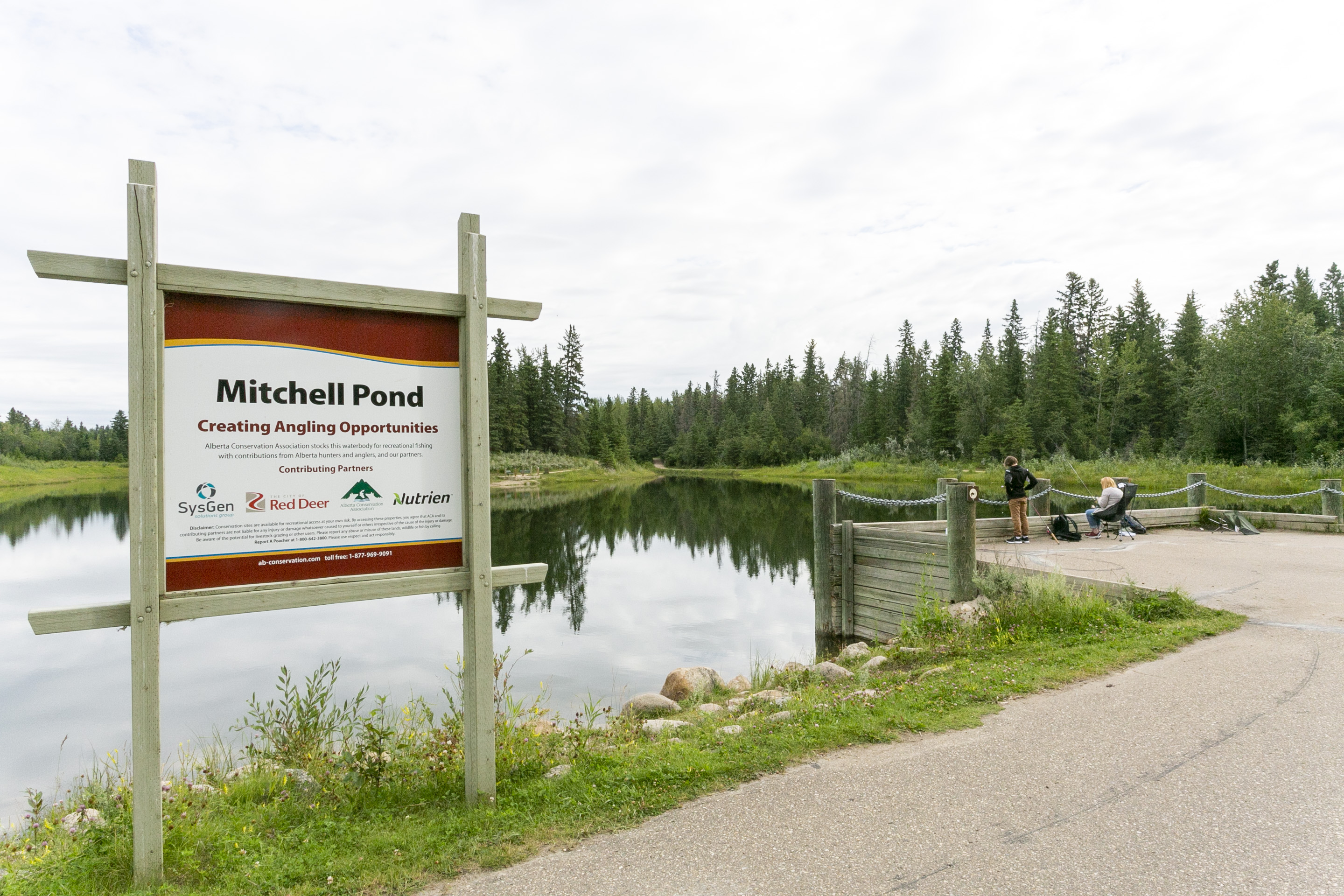 A couple sit in their camp chairs fishing off at dock at Michell Pond in lower Heritage Ranch