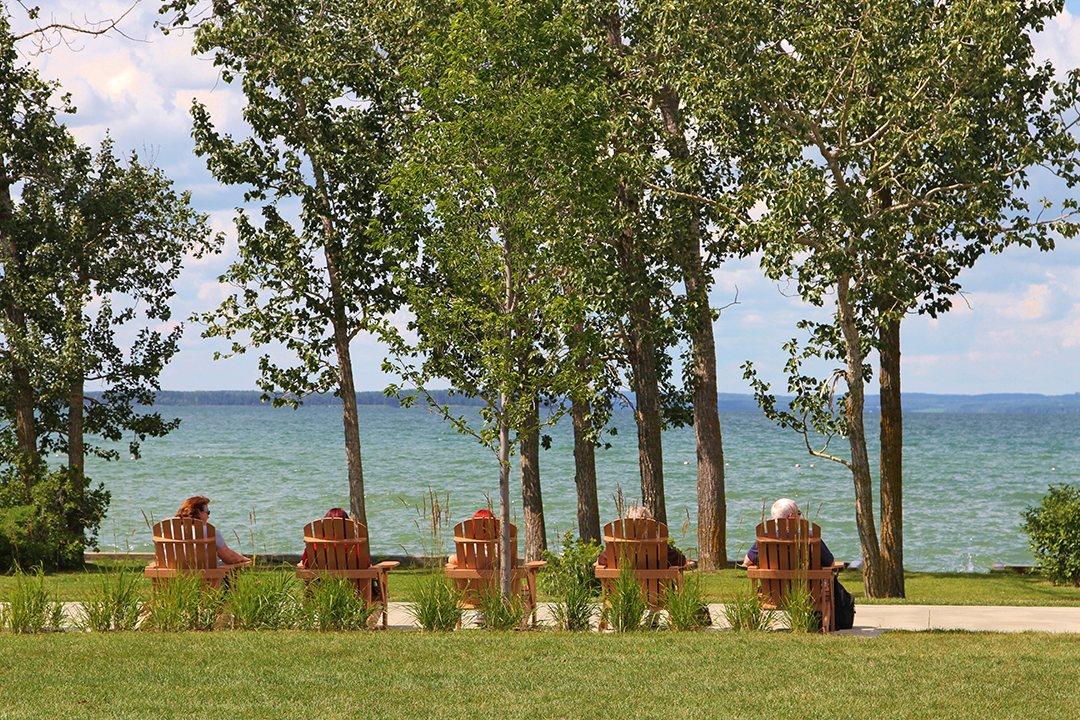 Two people enjoying Sylvan Lake on patio chairs 