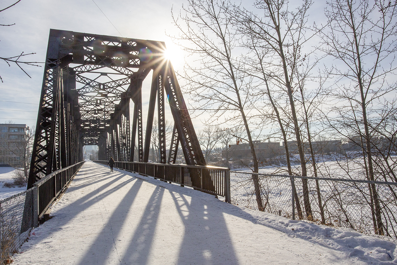 Lady walking across Canadian Pacific Railway Bridge in wintertime.