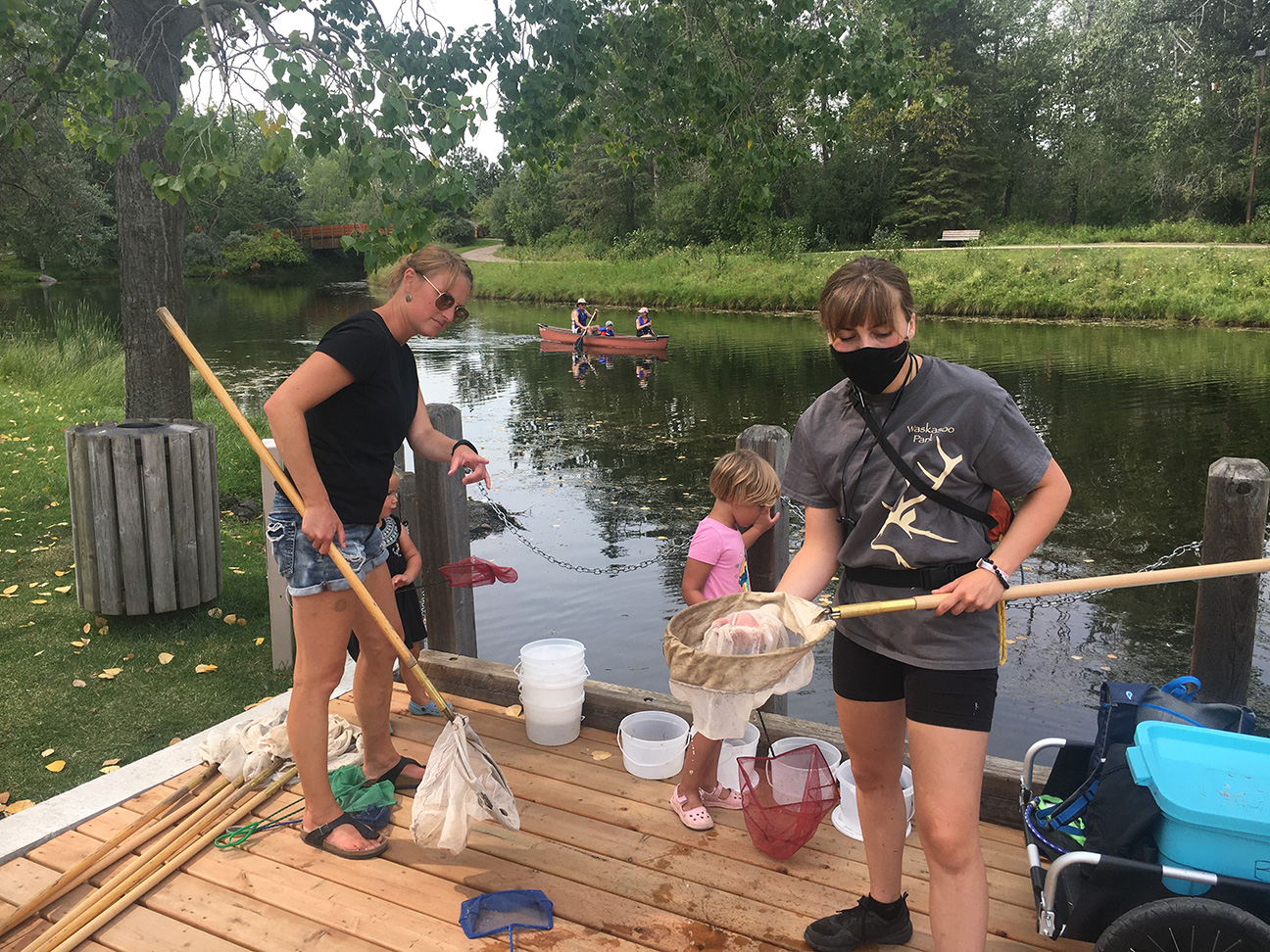 Kerry Wood Nature Centre staff showing children how to dip nets into the pond to explore plants and bugs