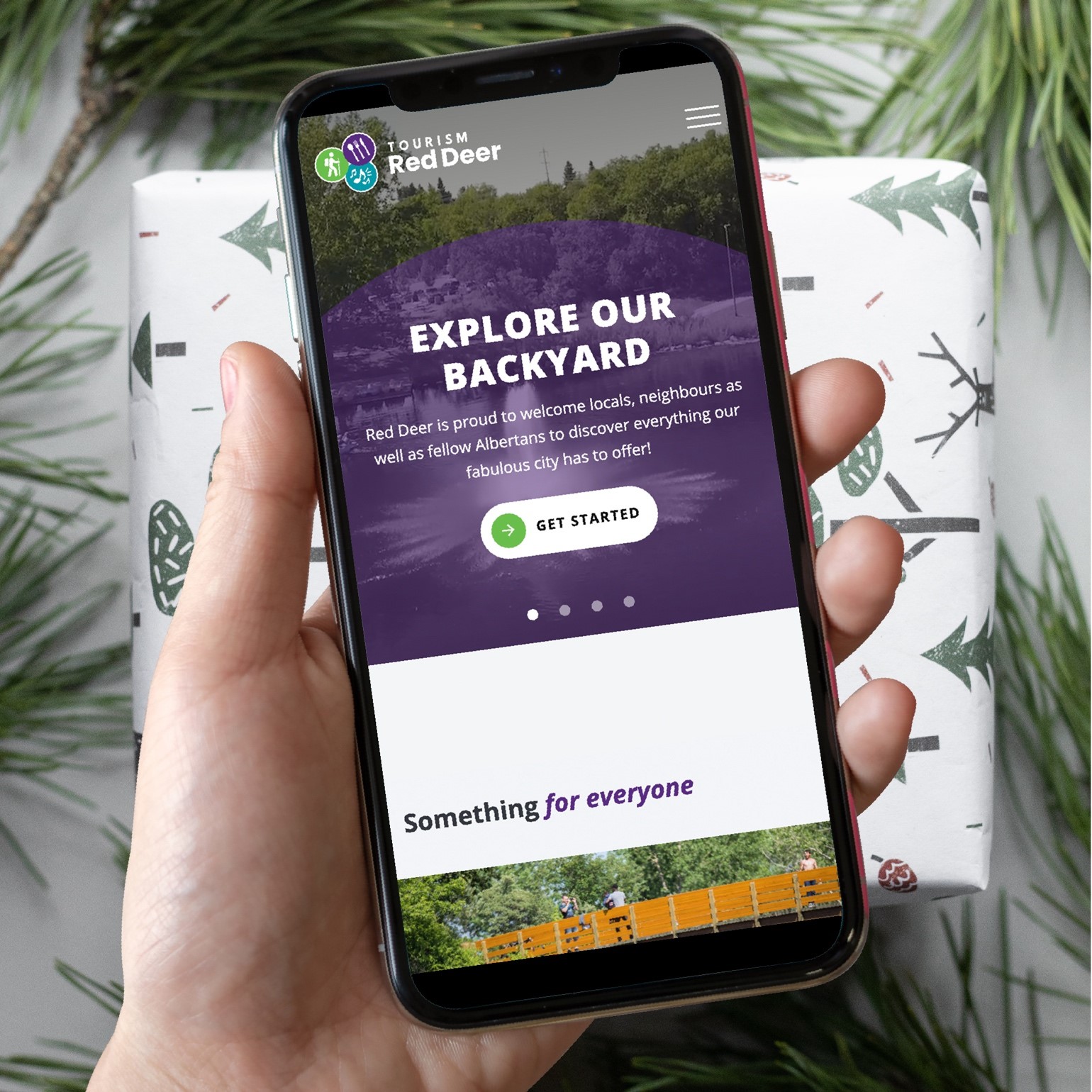 Someone holding a smartphone looking at the new Tourism Red Deer website. 