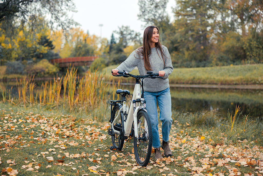 Girl standing next to her EBike in the Fall Autumn at Bower Ponds in Red Deer.