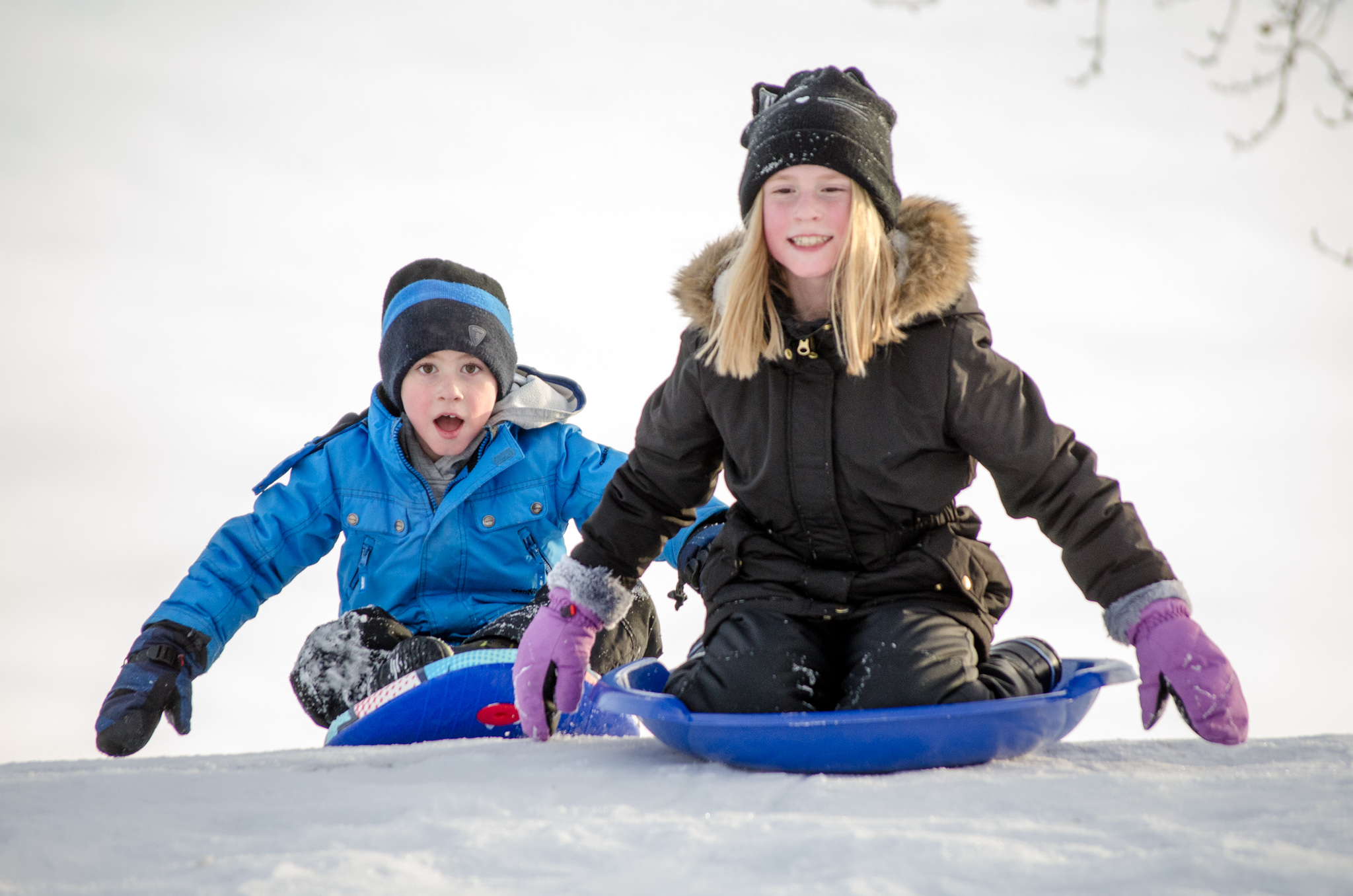 Two kids sledding down a hill in Red Deer, Alberta.